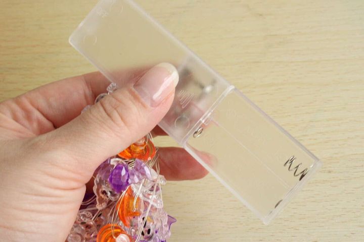 女性の指がダイソーLEDガーランドライトの電池ケースを持っている