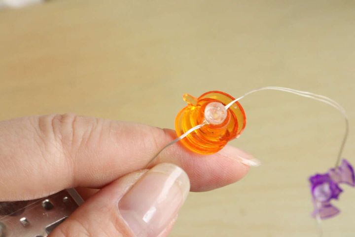女性の指がガーランドライトのかぼちゃモチーフからLED球が外れた状態を見せている