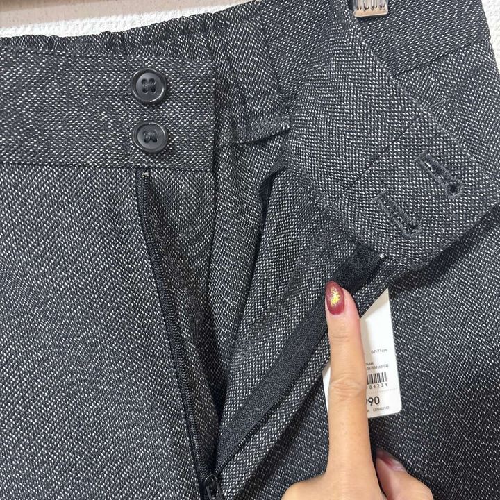 女性の指がGUツイードパンツのウエスト部分のボタンとファスナーを示している