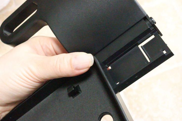 女性の手が車用トレイのテーブル部分とアームを接続している