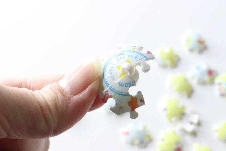 指で球体パズルのピースを一つ持っている様子。ピースのカーブと絵柄がよくわかる。
