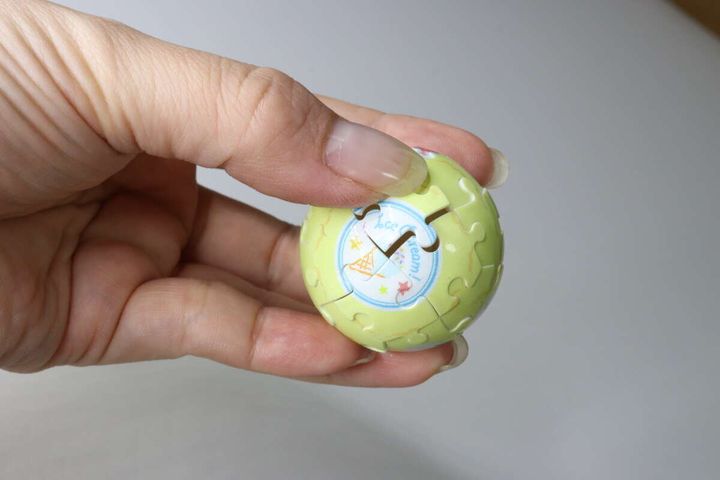 完成した球体パズルを手のひらで包むように持っている様子。パズルの絵柄が確認できる。