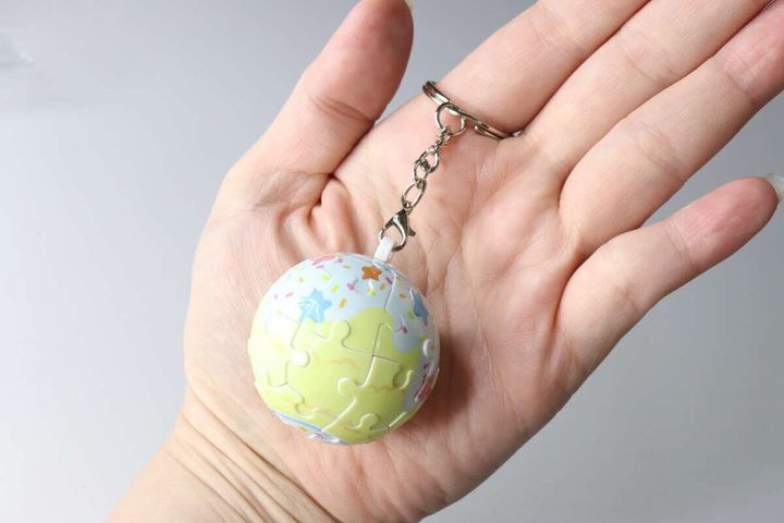完成したキーチェーン付き球体パズルを手のひらに乗せている様子。キーチェーンの金具も見える。