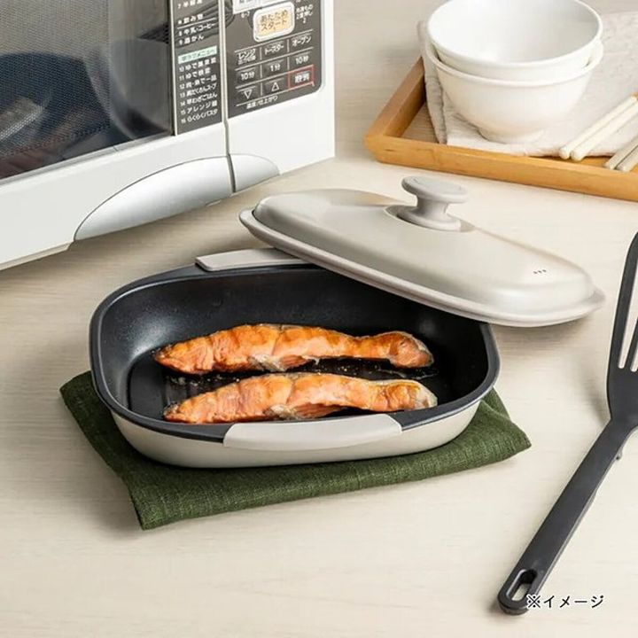 電子レンジの前に置かれたグリルプレートで焼かれた鮭の切り身