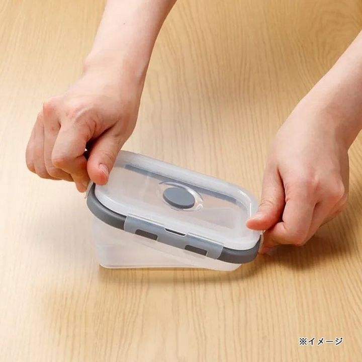 両手で折りたたみ保存容器をたたんでコンパクトにしている様子