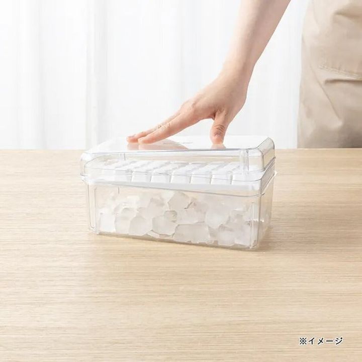 女性がプッシュ式製氷器の蓋を押し、下の容器に氷が落ちている様子