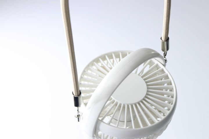 白いハンディファンがベージュのストラップで吊るされている