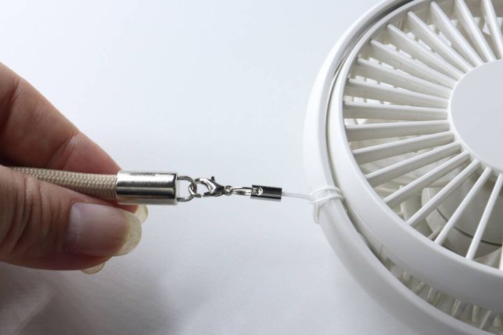 ハンディファンにストラップの白い紐を取り付けている