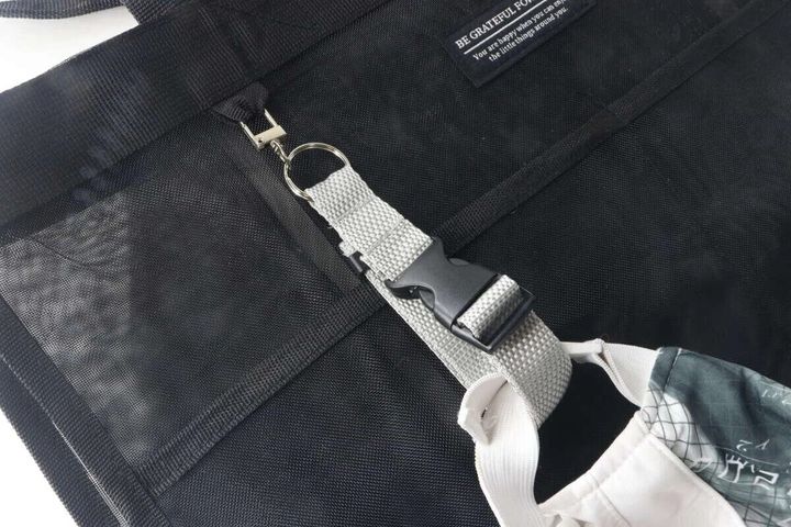 黒いバッグにグレーのベルトキーホルダーで白いキャップを吊り下げている様子