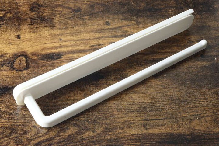木目のテーブルに置かれたダイソー粘着スライド式タオルフックの本体（収納時）