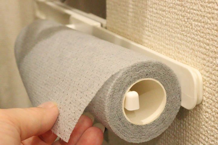 壁のタオルフックからロールたわしを引き出す女性の手元