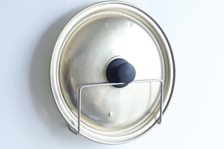 吸着シート付きホルダーに銀色の鍋ふたが立てかけられている