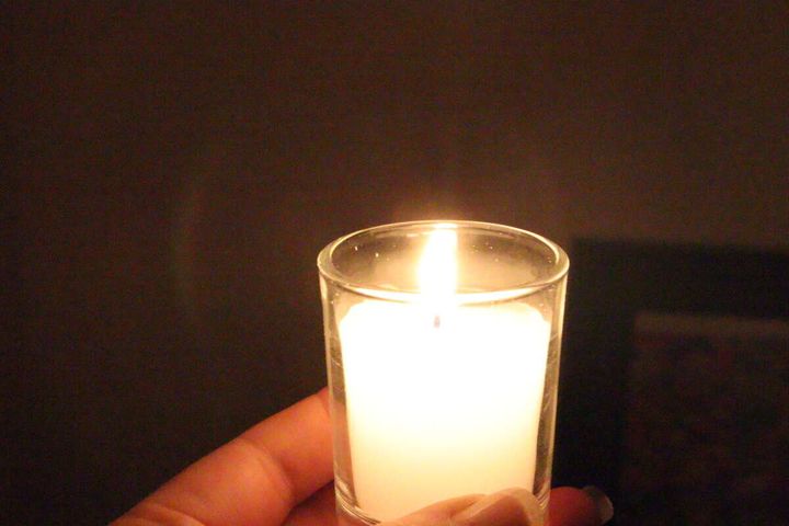 暗闇で女性の手に持たれたローソクが灯る