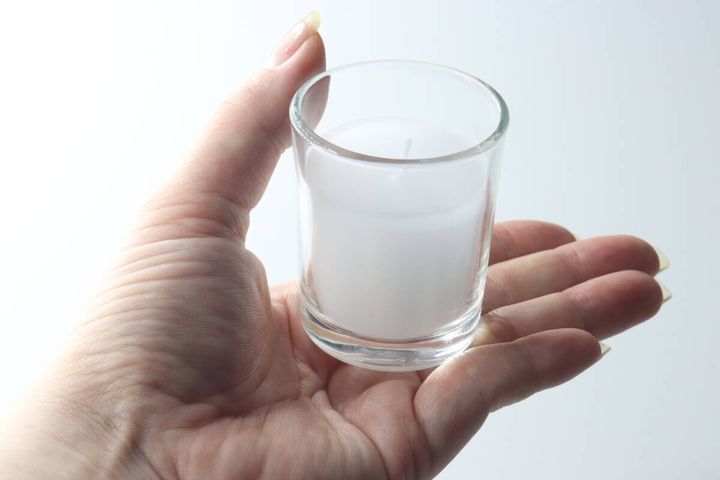 女性の手に乗せられたガラス容器入りローソク