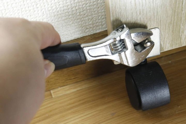 女性が家具のキャスターをモンキーレンチで調整している