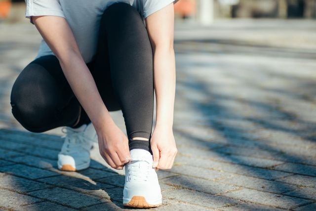 これからランニングをする女性イメージ シューズの靴紐を結ぶ