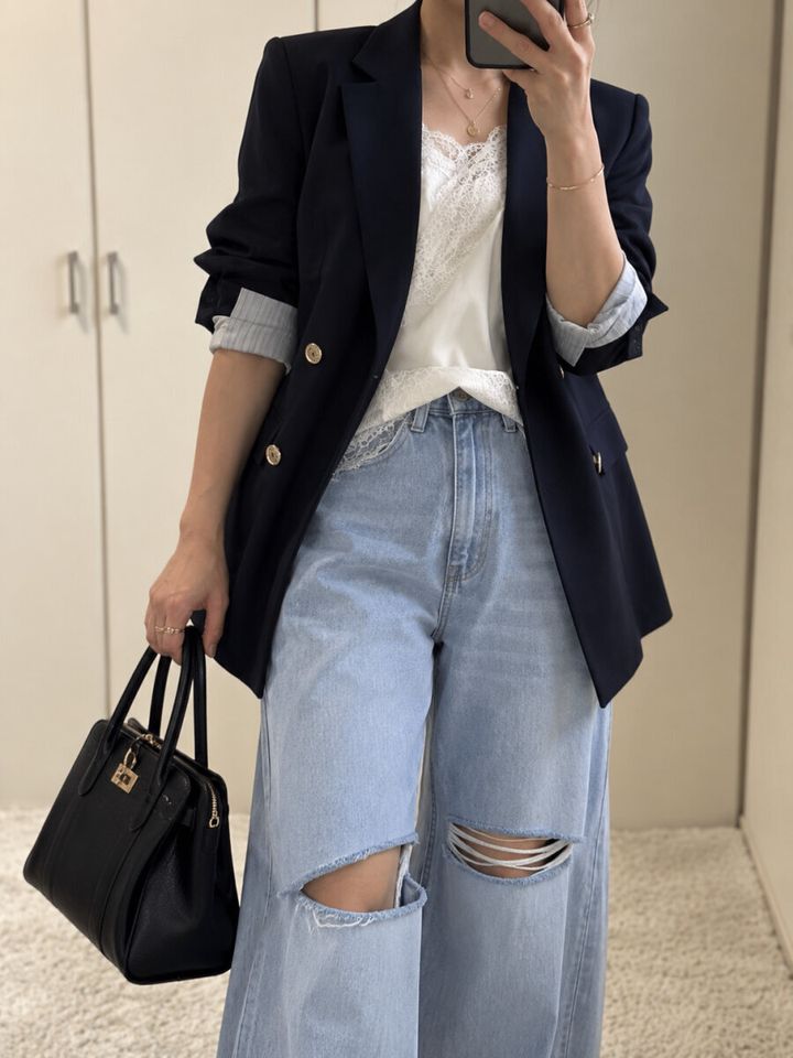 ネイビーJKと白レーストップス、カーブデニムの女性がスマホで自撮り