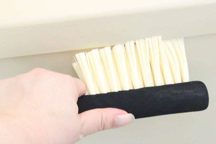 女性の手がダイソー洗車ブラシでお風呂の壁の角を掃除している