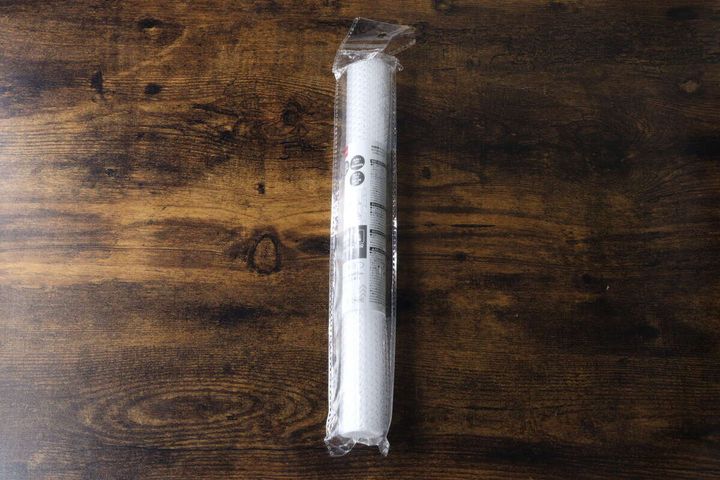 木目のテーブルに置かれた、ロール状に包装されたダイソーの冷蔵庫マット
