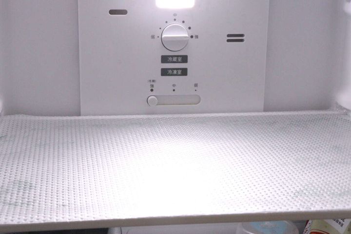 冷蔵庫の棚に敷かれたクリアな冷蔵庫マット。奥に温度調節ダイヤルが見える