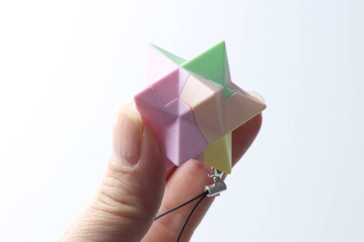 女性の指で持たれた、組み立て途中のパステルカラーの頭脳パズル
