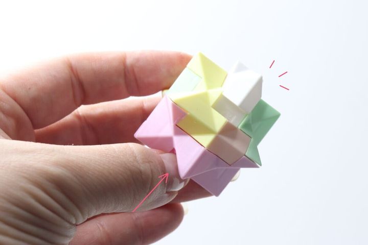 女性が頭脳パズルキーホルダーの白いパーツを押し込んで分解している様子