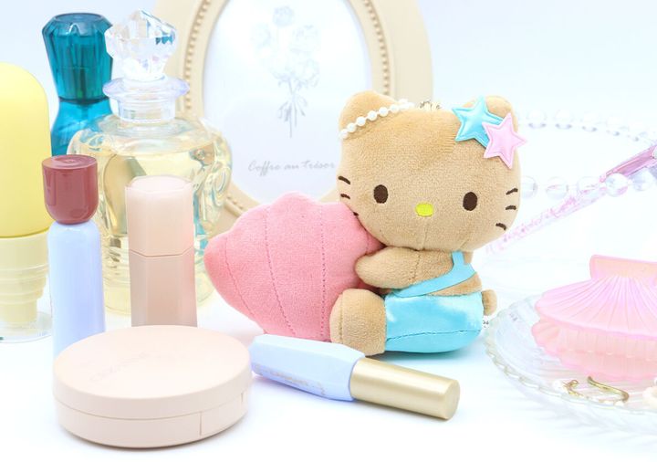 日焼けキティのぬいぐるみチャームが香水瓶や化粧品と一緒に飾られている