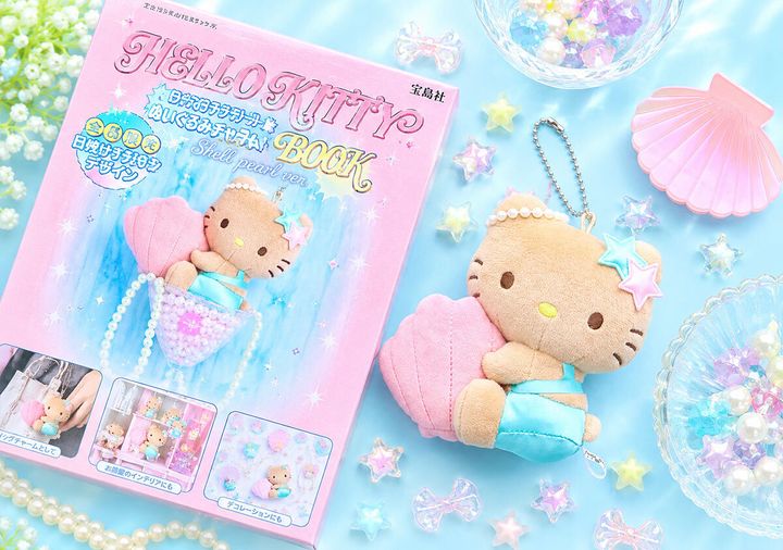 「HELLO KITTY ぬいぐるみチャームBOOK」と日焼けキティチャーム、貝殻や星の装飾品が並べられた俯瞰
