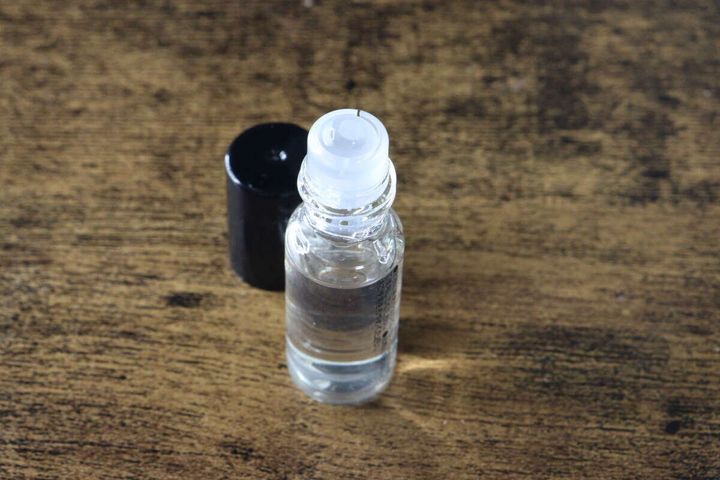 セリアのロールオンフレグランスのボトルがキャップを外した状態で木目調の台に置かれている