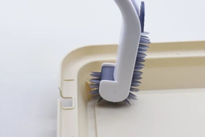 L字型ブラシでクリーム色の排水口の角を掃除している