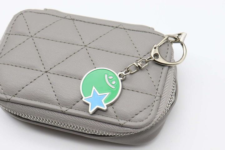 グレーのキルティングポーチに付けられたメタルキーホルダー