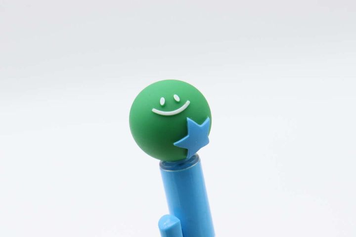 ボールペンの先端にある緑色の太陽と星のマスコットのアップ