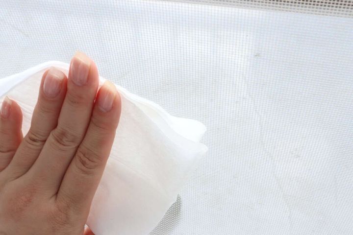 女性が網戸用おそうじシートで網戸を拭いている様子