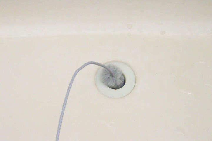 洗面台の排水口にパイプクリーナーのブラシ部分が差し込まれている様子
