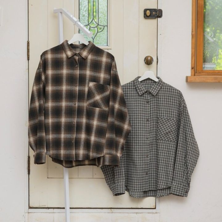 茶色とグレーのチェック柄シャツ2枚が白いドアに掛けられている