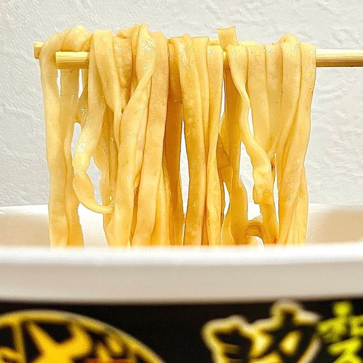 日清食品の「日清のどん兵衛 特盛和スパイスカレーきつねうどん」の麺を箸でつかむ