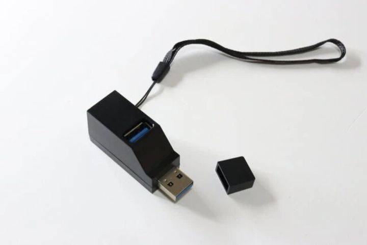 黒いUSBハブがキャップを外して置かれ、ストラップが付いている