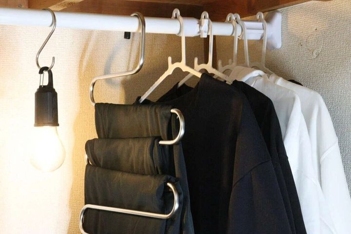 つっぱり棒に吊るされた黒と白の服、S字フックの電球
