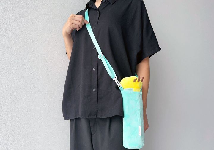 黒い服の女性がニャッキホルダーを斜め掛けしている