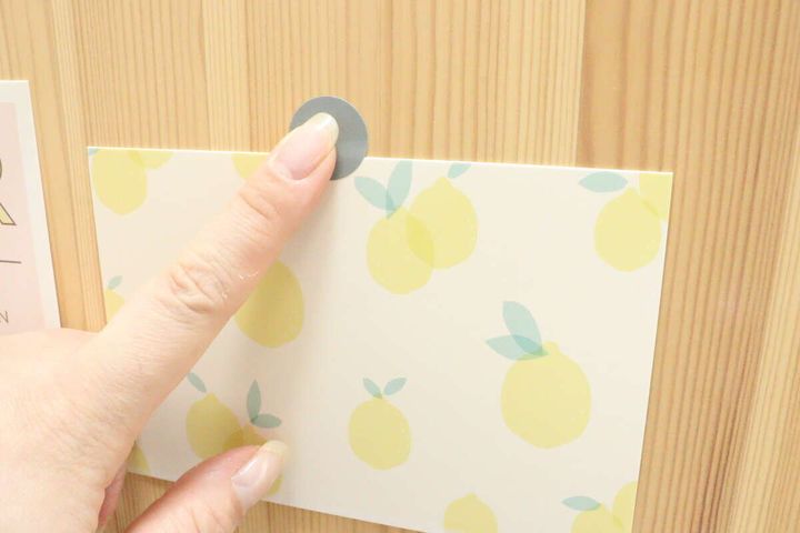レモン柄のカードを壁にシールで貼る様子