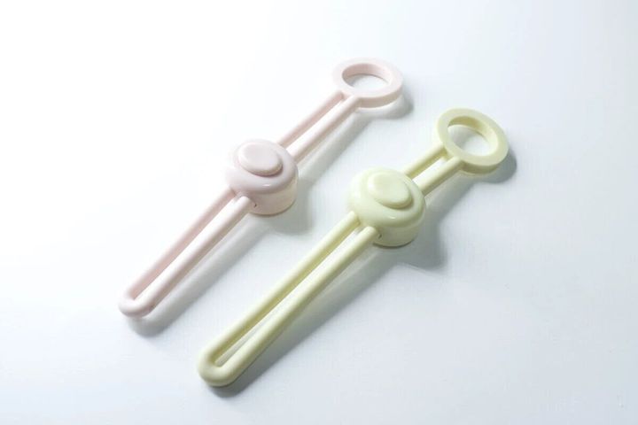 ピンクと黄緑色の調節できる輪ゴムクリップが2つ並んでいる