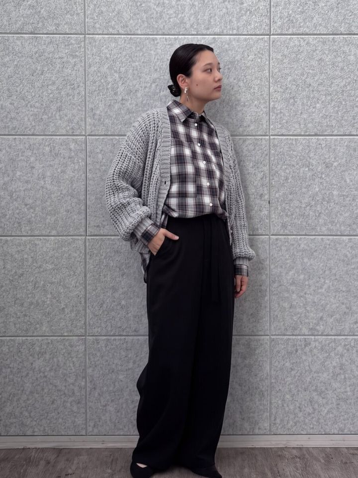 チェックシャツにざっくりグレーカーデを羽織った女性