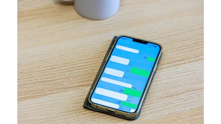 机の上に置かれたメッセージアプリのトーク画面を表示しているスマートフォン