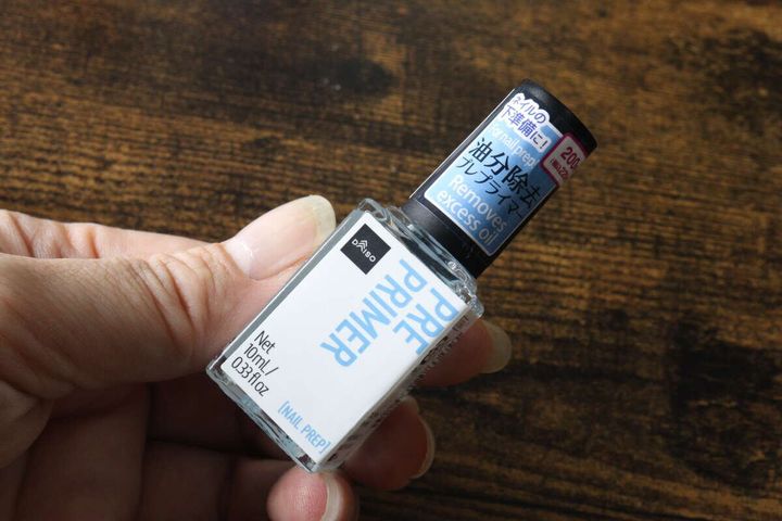 女性がダイソーのプレプライマーボトルを手に持ち、斜めから見せている