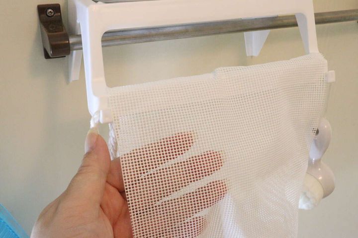 浴室のバスラック下部のバーにメッシュの袋を掛けている様子を拡大