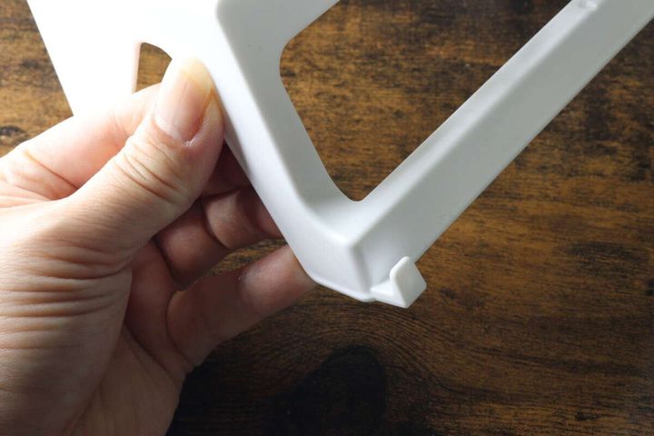 白いバスラックの裏側にあるタオルバーに差し込む部分を指で示している