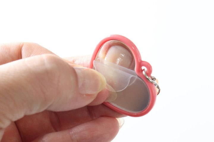 リップミラーの鏡の保護フィルムを剥がす手元