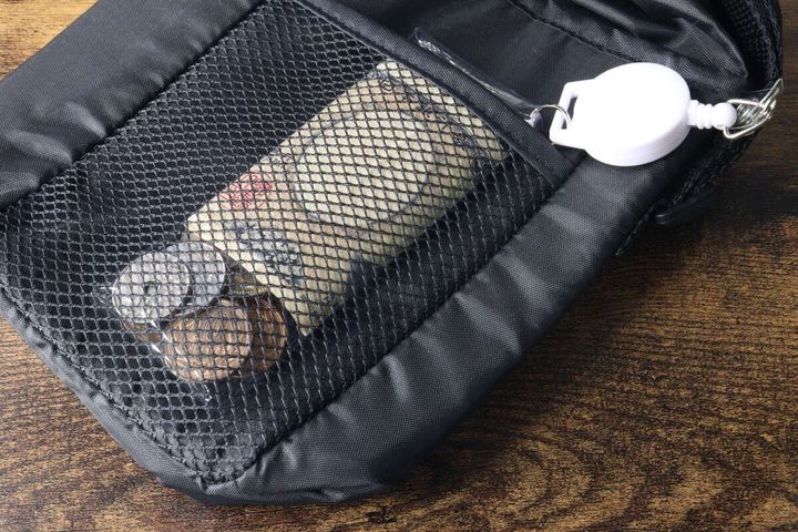 黒いメッシュポケット付きバッグに、透明ポーチに入った千円札と小銭が収納されている