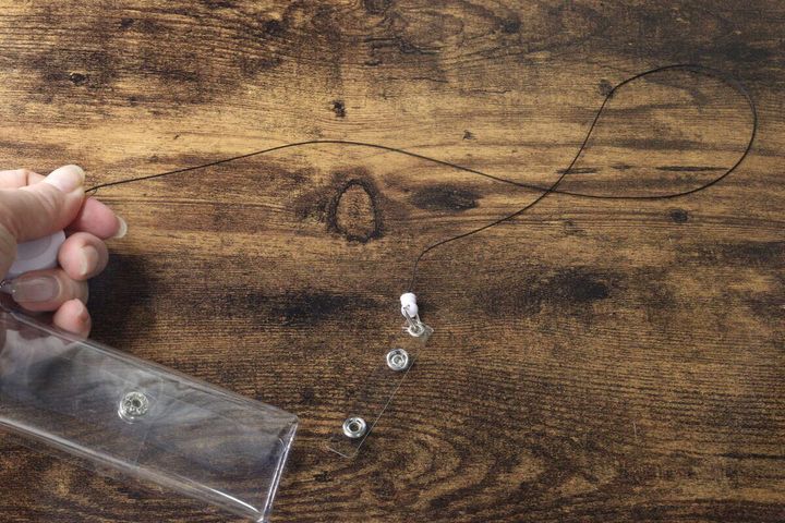 左手で透明ポーチを持ち、リールが長く伸びた状態を指でつまんでいる様子