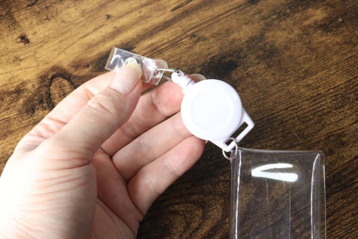 女性の指がリール部分の金具とポーチの接続部分を指し示しているクローズアップ